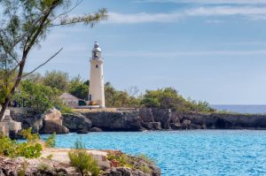 Witte vuurtoren Negril Lighthouse op een rotsachtige landtong met helder blauwe zee op de achtergrond