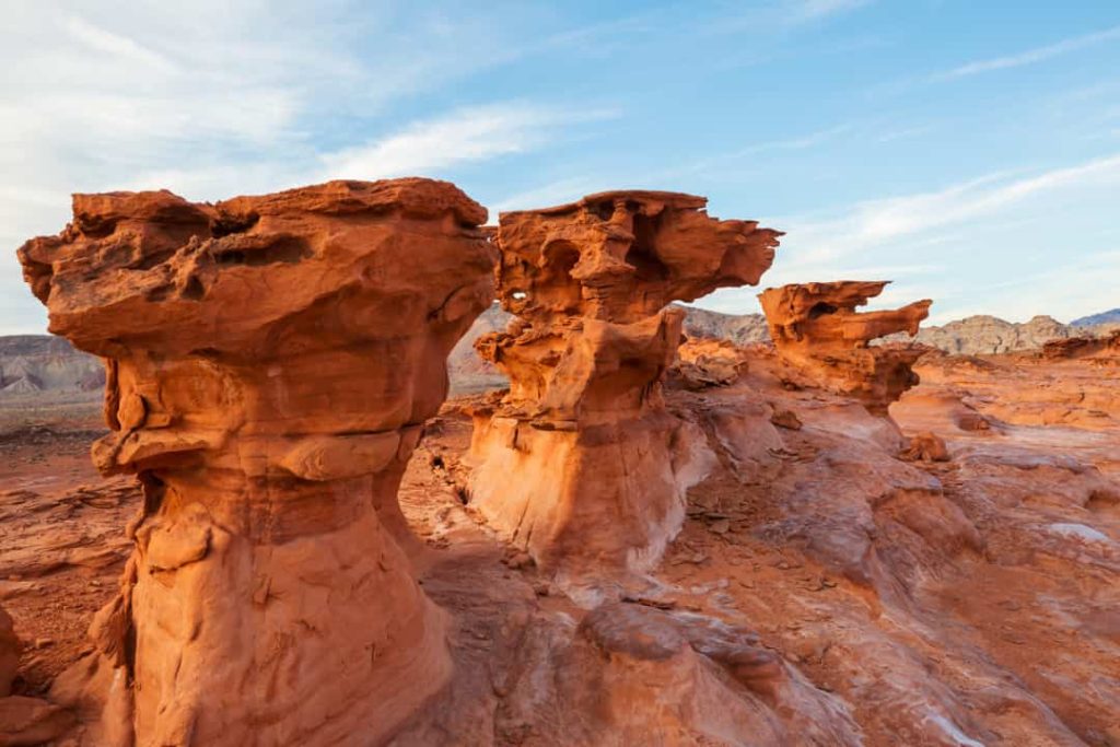 Rij oranje zandstenen rotsformaties met brede bovenkant, geërodeerd tot paddenstoelvorm, in een woestijnlandschap in Nevada