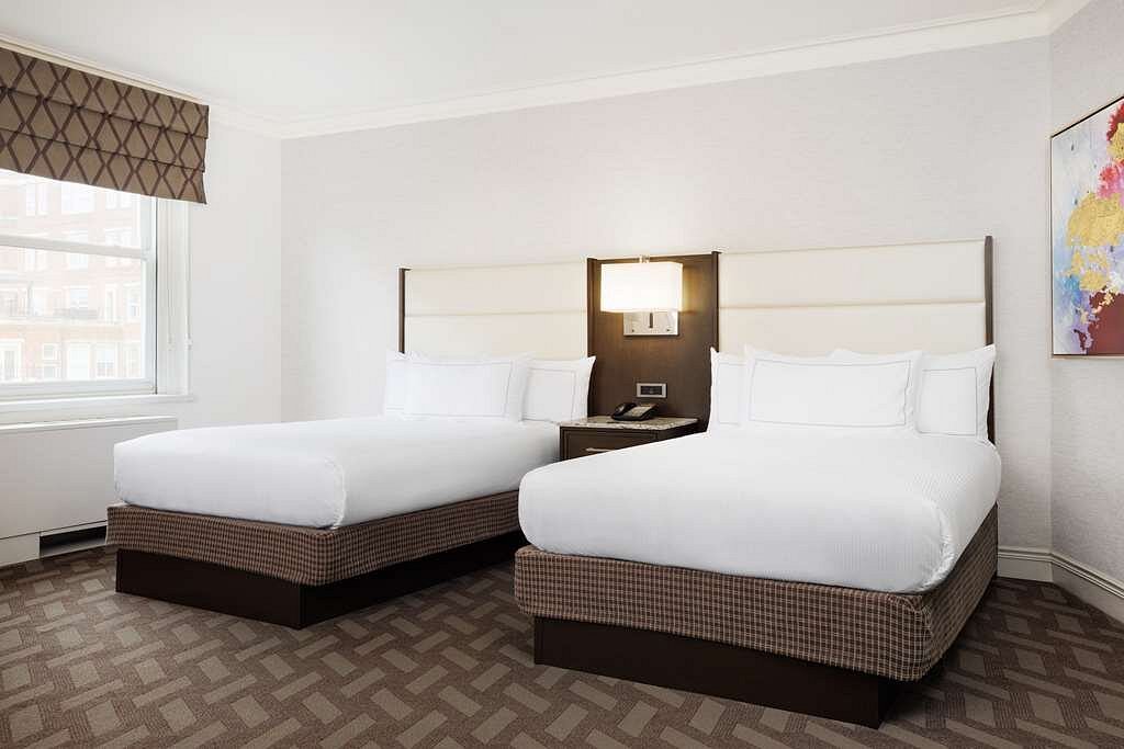 Nette hotelkamer met twee opgemaakte bedden met geruite bedsprei, een geruite gordijnen en een geruit tapijt