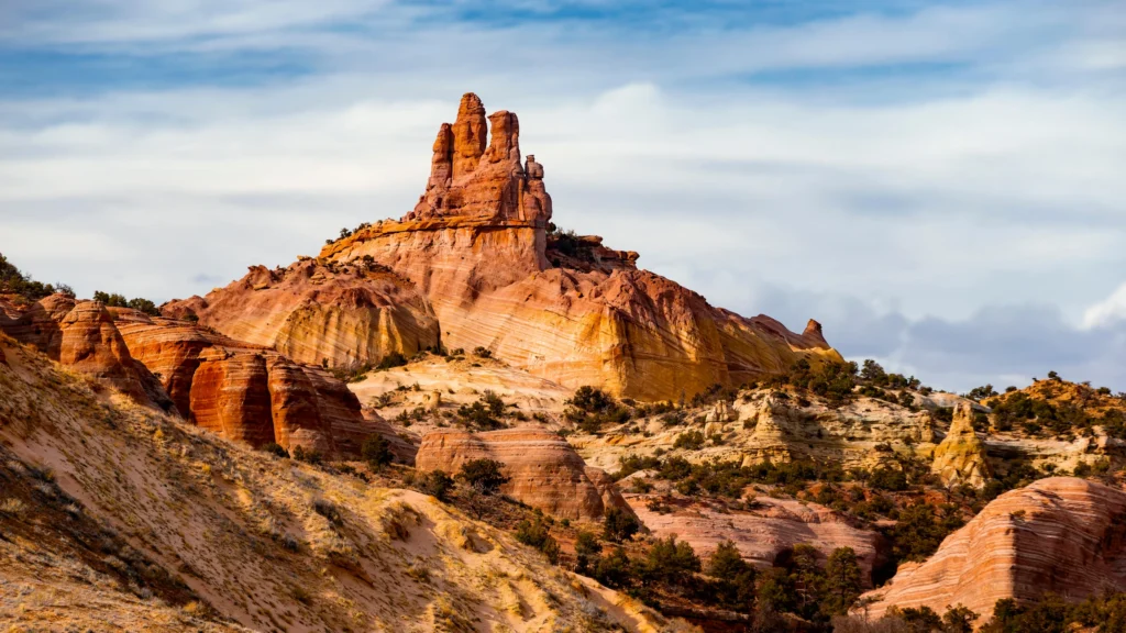 Opvallende gelaagde rode rotsformatie die boven een geerodeerd woestijnlandschap uitsteekt in New Mexico