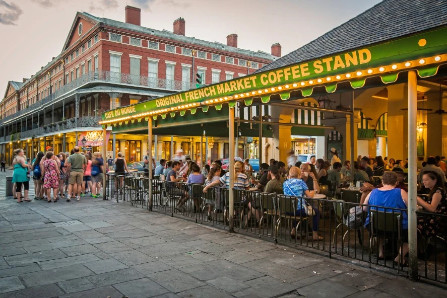 Bezoekers zitten op het overdekte terras van het beroemde Café du Monde in de French Quarter van New Orleans bij avondlicht