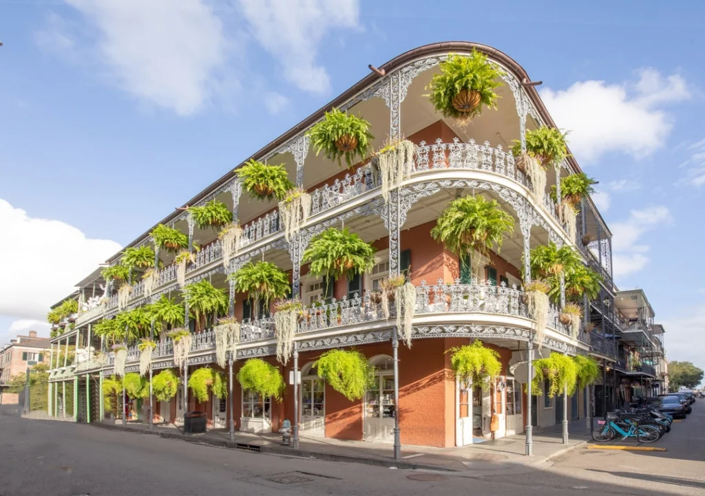 Historisch hoekpand met twee verdiepingen smeedijzeren balkons vol hangende varens in de French Quarter van New Orleans