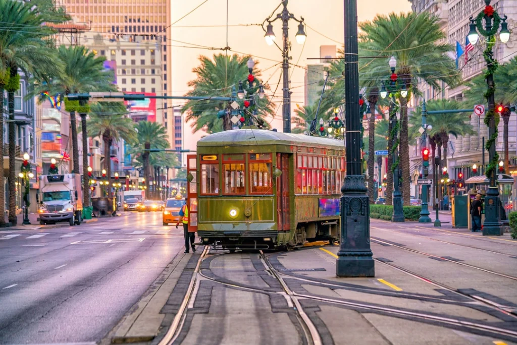Groene houten tram rijdt over de rails in de brede Canal Street met palmbomen en kerstverlichting in New Orleans