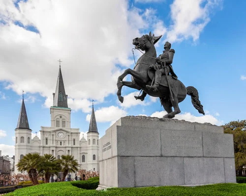 Bronzen ruiterstandbeeld op een sokkel met op de achtergrond de witte torens van de St. Louis Cathedral in New Orleans