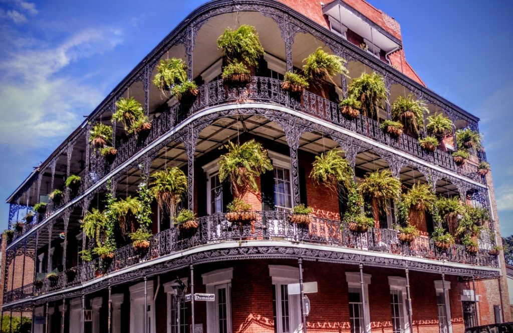 Bakstenen gebouw met meerdere verdiepingen smeedijzeren balkons vol hangende groene varens in het Franse Kwartier van New Orleans