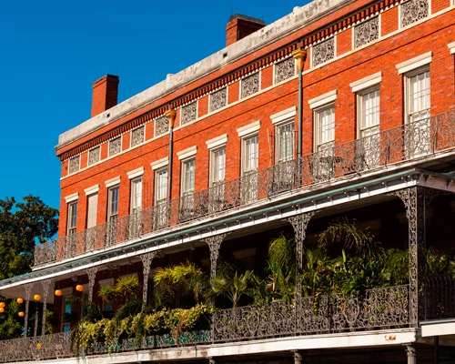 Historisch rood bakstenen pand met sierlijke smeedijzeren balkons vol planten in de French Quarter van New Orleans