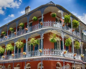 Rood bakstenen hoekgebouw met twee verdiepingen smeedijzeren balkons vol hangende varens in de French Quarter van New Orleans