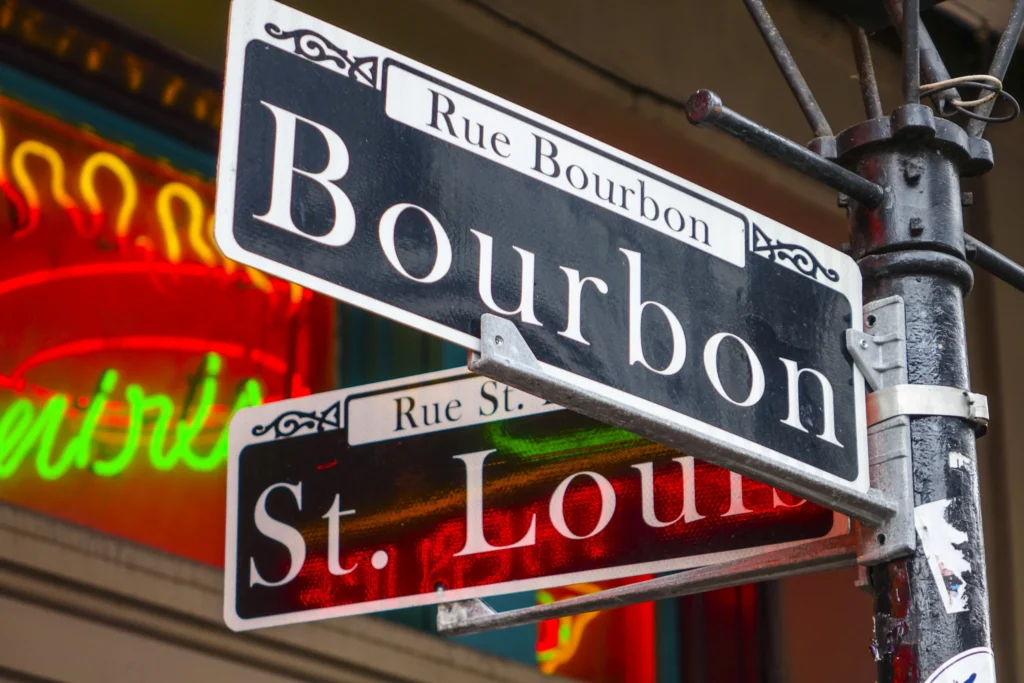 Zwart wit straatnaambordje van Bourbon Street en St Louis Street met neonreclame op de achtergrond in New Orleans