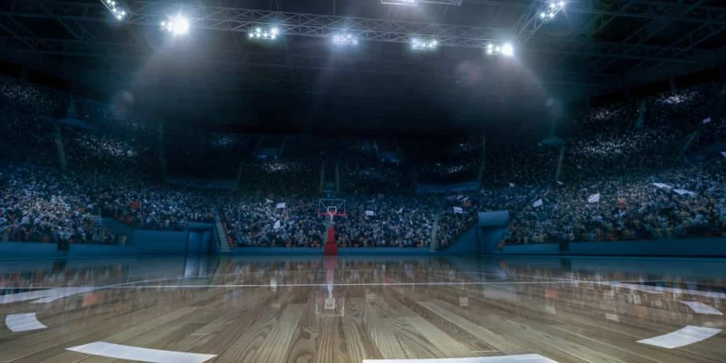 Weids beeld van een leeg basketbalveld in een arena met duizenden toeschouwers op de tribunes eromheen