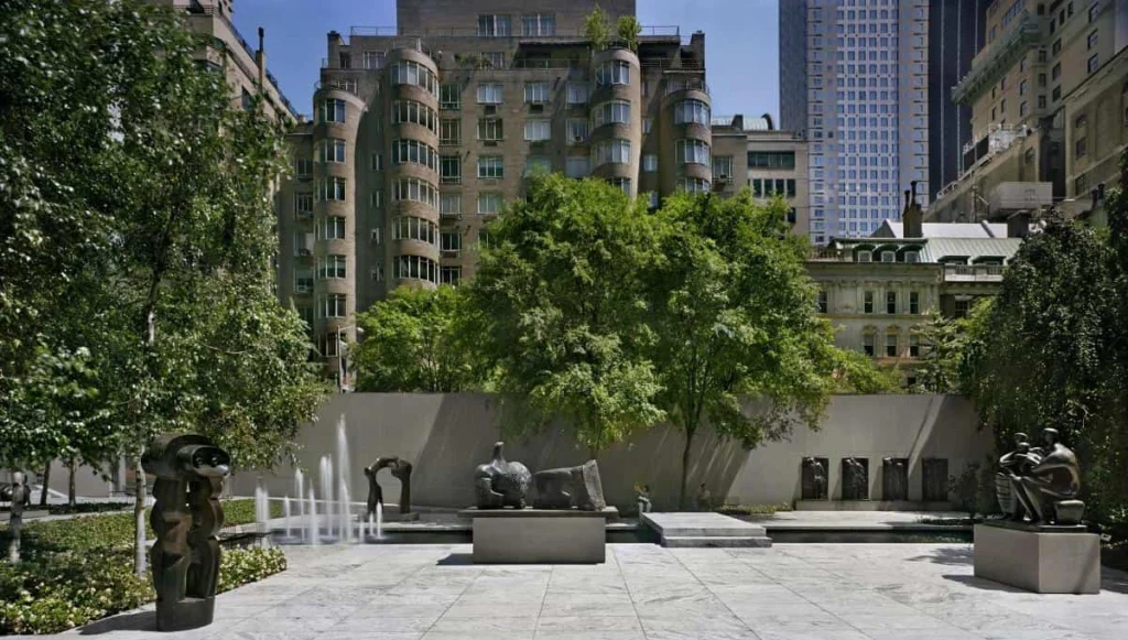 Beeldentuin van het Museum of Modern Art in New York met bronzen sculpturen, een fontein en groene bomen tegen de achtergrond van gebouwen in Manhattan