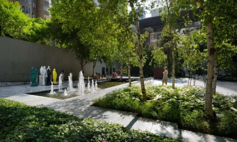 Beeldentuin van het Museum of Modern Art in New York met witte sculpturen, fonteinen en groene bomen tussen de gebouwen