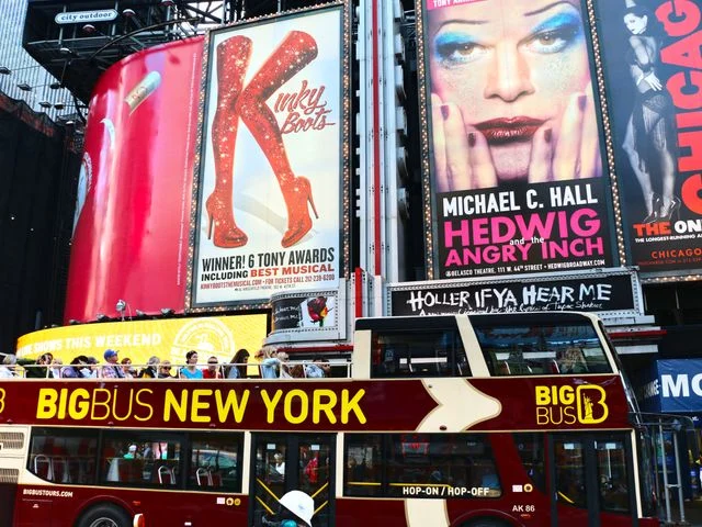 Rode dubbeldekker toeristenbus rijdt over Times Square in New York langs grote reclameborden voor Broadwayshows