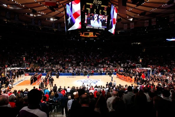 Overzicht van het basketbalveld en de volle tribunes met een groot scherm aan het plafond in Madison Square Garden