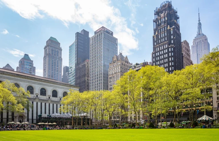 Grasveld in Bryant Park omzoomd door bomen met jong lentegroen en op de achtergrond de skyline van Manhattan