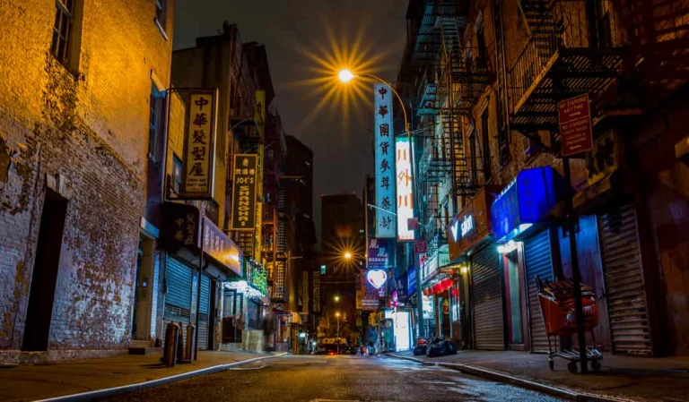 Lege straat in Chinatown New York in de avond met neon verlichte gevels, Chinese opschriften en brandtrappen aan de gebouwen