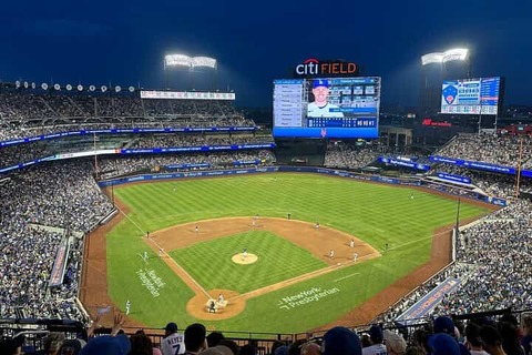 Verlicht honkbalstadion Citi Field vol toeschouwers tijdens een avondwedstrijd met het scorebord op de achtergrond