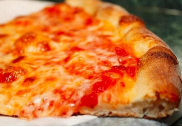Close-up van een dampende punt pizza met gesmolten kaas en tomatensaus op een bruine korst