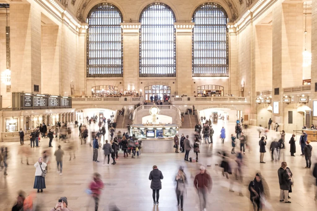 Statige gewelfde doorgang in Grand Central Terminal met bolvormige kroonluchters en reizigers die op de achtergrond lopen