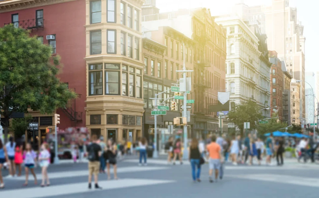 Wazig gefotografeerde voetgangers steken een drukke kruising over tussen negentiende-eeuwse gebouwen in de buurt van Union Square in New York