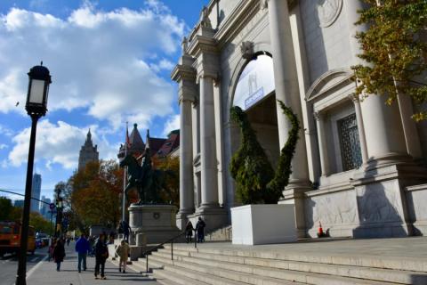 Bezoekers lopen langs de stenen zuilen en het ruiterstandbeeld bij de ingang van het American Museum of Natural History