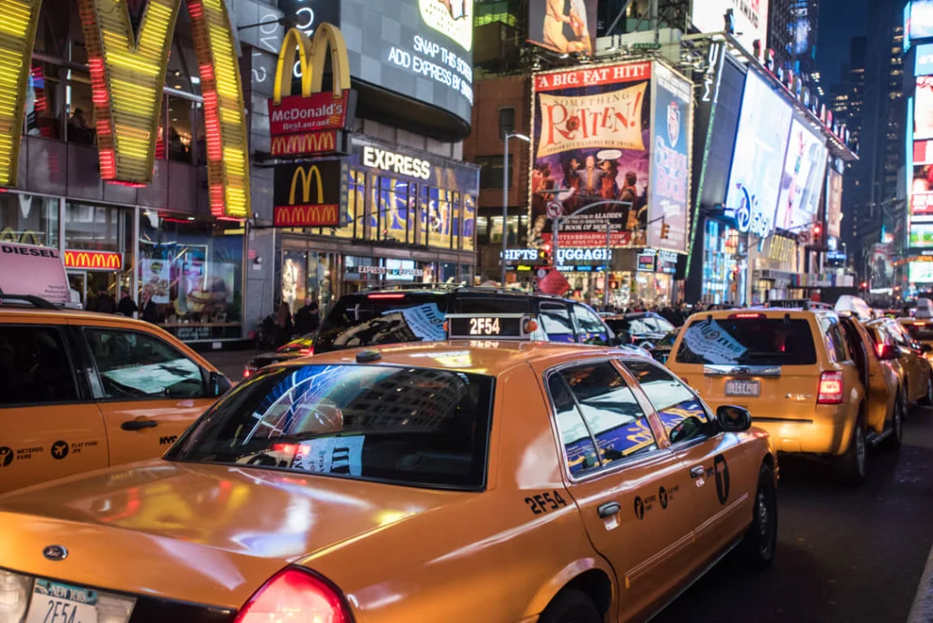 Rij gele taxi's staat stil in het verkeer bij verlichte reclameborden en winkels op Times Square in New York