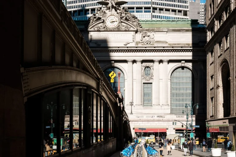 Klassieke natuurstenen gevel van Grand Central Terminal gezien vanaf straatniveau met de spits van de Chrysler Building erachter