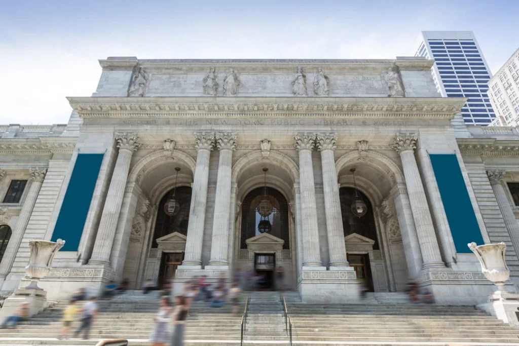 Klassieke voorgevel van de New York Public Library met bogen, zuilen en bezoekers op de brede trap overdag