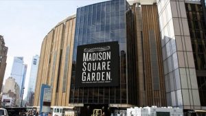 Grote gevel van Madison Square Garden met het logo op een groot scherm boven de ingang en voorbijgangers op straat