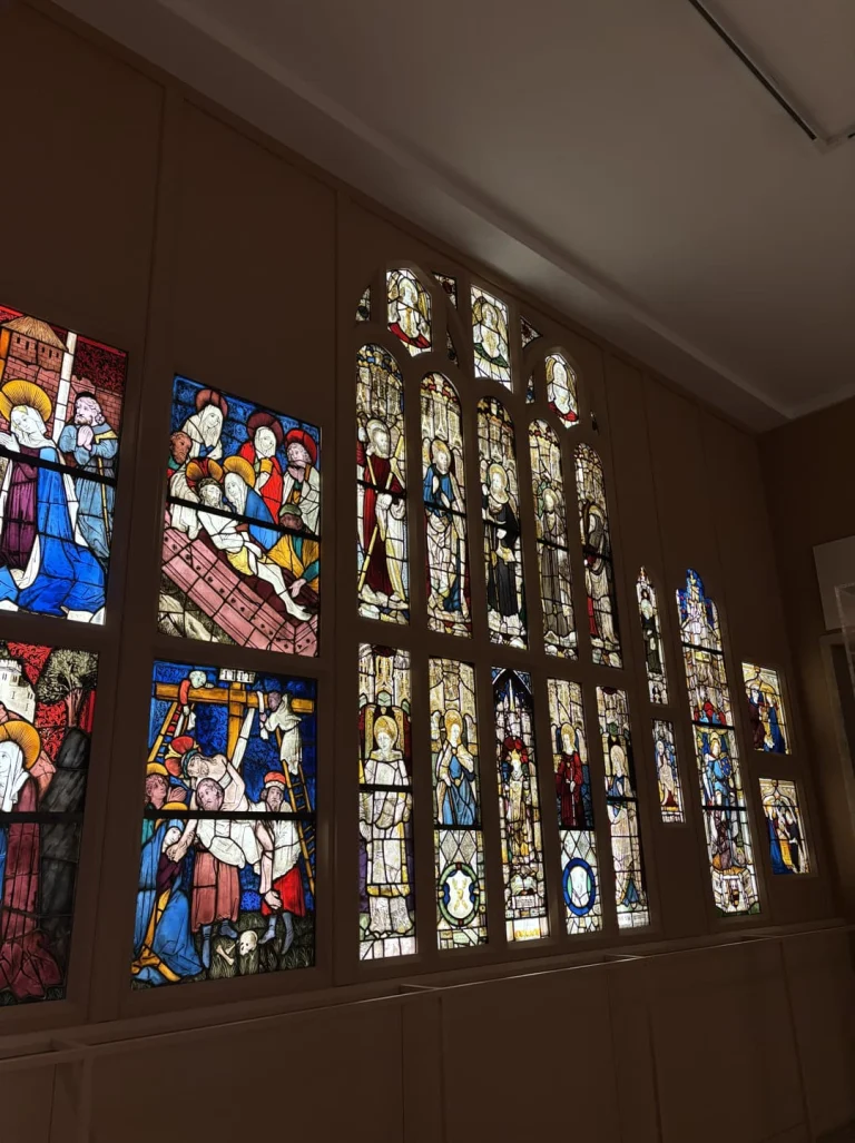 Rij kleurrijke glas in loodramen met religieuze taferelen tentoongesteld in een zaal van het Metropolitan Museum of Art in New York
