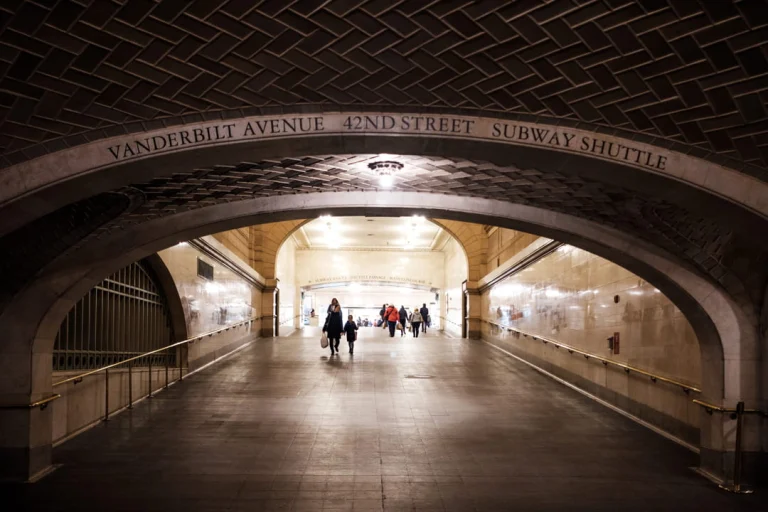 Close-up van de bekende gouden vierzijdige klok in Grand Central Terminal met een grote Amerikaanse vlag op de achtergrond