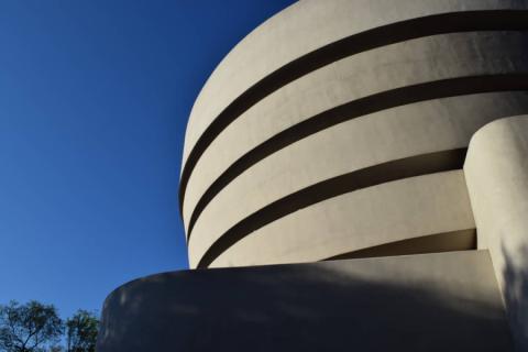 Close-up van de ronde witte spiraalvormige gevel van het Guggenheim Museum tegen een strakblauwe lucht