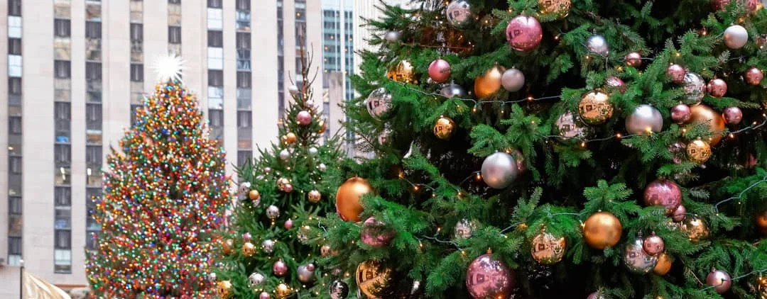 Twee versierde kerstbomen met gouden en zilveren ballen voor de wolkenkrabbers van Rockefeller Center in New York