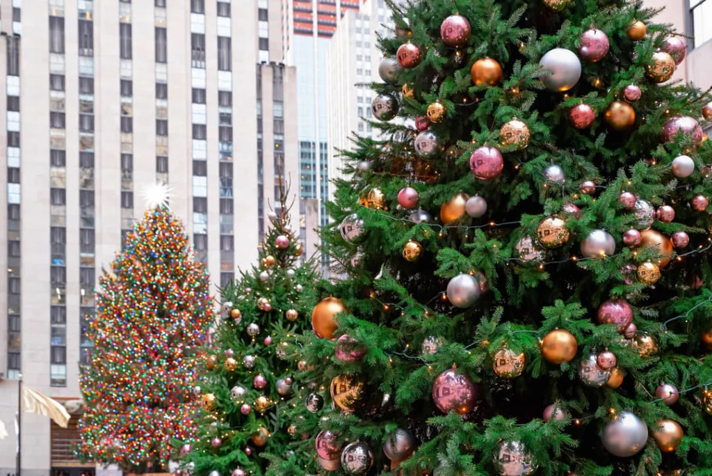 Close-up van een kerstboom met gouden en zilveren ballen met de verlichte kerstboom van Rockefeller Center op de achtergrond