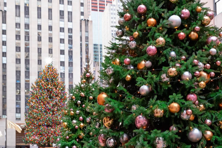 Close-up van kerstbomen versierd met roze, zilveren en gouden kerstballen met gebouwen van het Rockefeller Center op de achtergrond