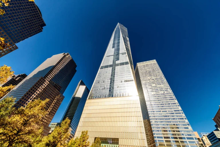 Laag standpunt tussen kantoorgebouwen met de glazen gevel van One World Trade Center die hoog de lucht in reikt