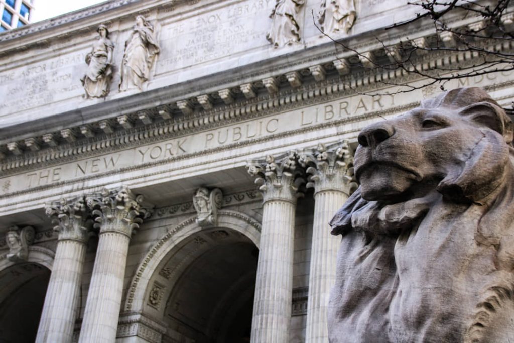 Close-up van een van de stenen leeuwenbeelden voor de zuilengevel met het opschrift New York Public Library