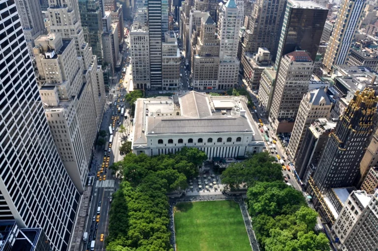 Luchtfoto van het grasveld van Bryant Park naast de New York Public Library omringd door wolkenkrabbers en drukke straten