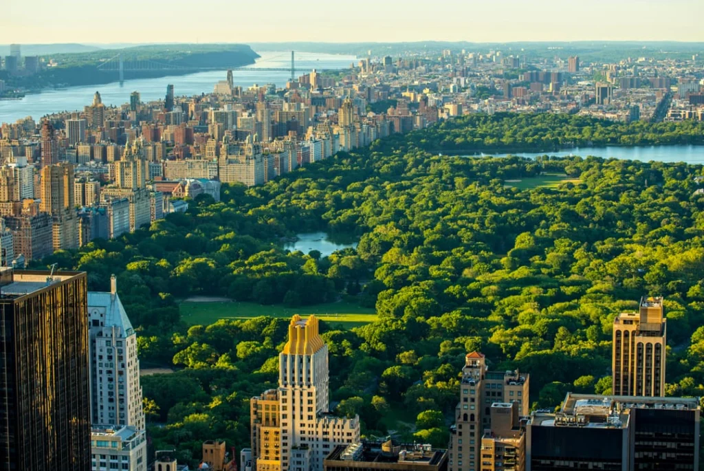Luchtfoto van het bosrijke Central Park met een brug en de Hudson rivier zichtbaar tussen de wolkenkrabbers van Manhattan