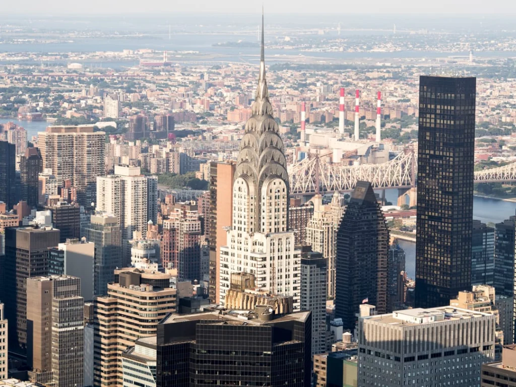 Luchtfoto van de gouden top van de Chrysler Building tussen wolkenkrabbers met de East River en een brug erachter