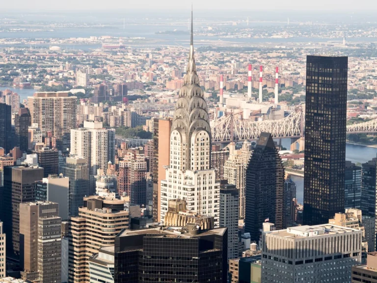 Luchtfoto van de gouden top van de Chrysler Building tussen wolkenkrabbers met de East River en een brug erachter
