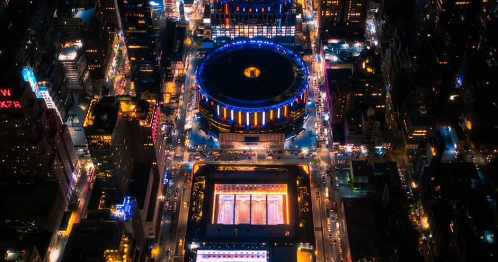 Luchtfoto bij nacht van Madison Square Garden in New York, omringd door verlichte gebouwen en drukke straten