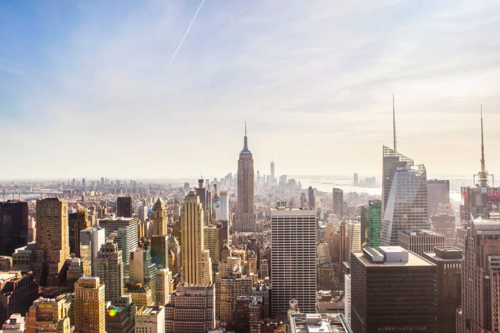 Wijds uitzicht vanaf een hoog observatiedek over de wolkenkrabbers van Manhattan met de spits van het Empire State Building zichtbaar