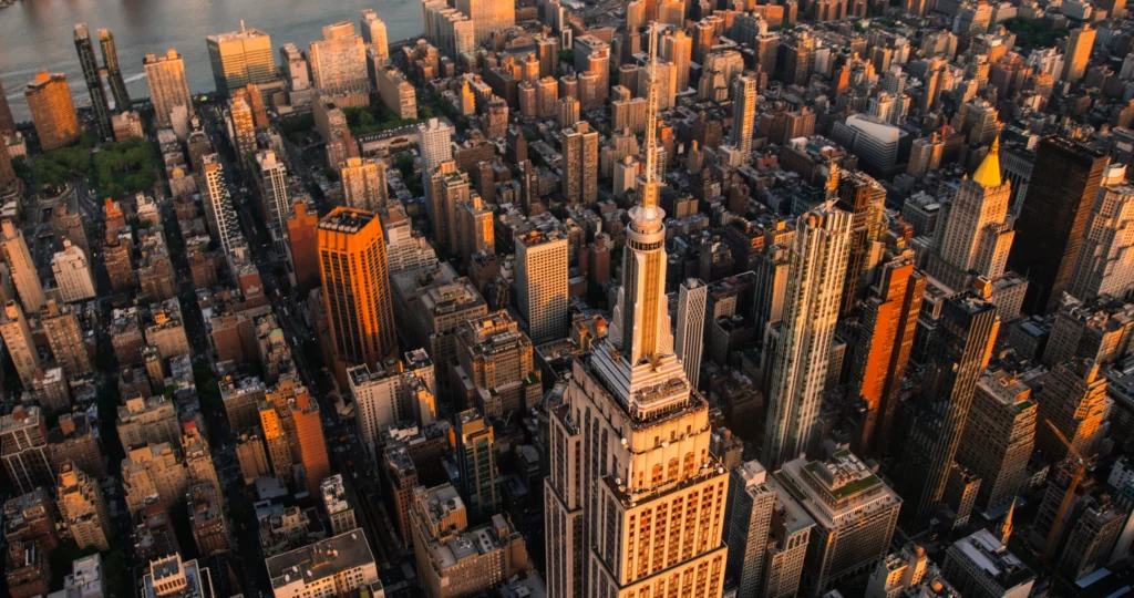 Luchtfoto van de dichte wolkenkrabbers van Manhattan met het Empire State Building op de voorgrond bij zonsondergang