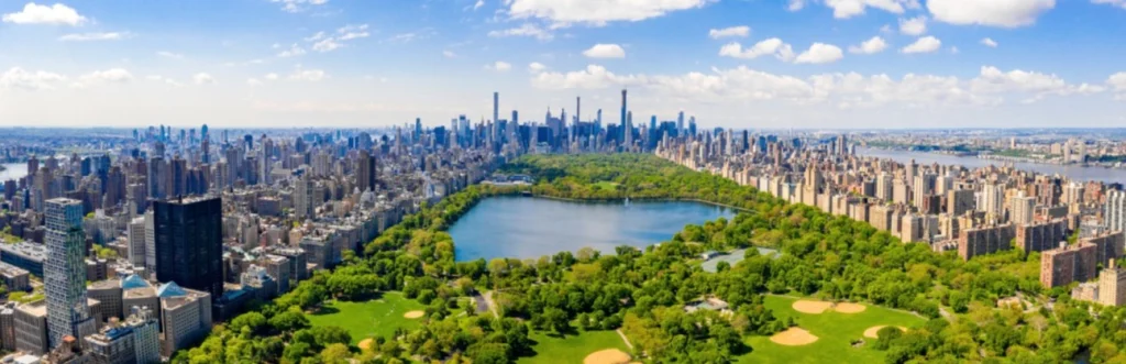 Breed luchtfoto panorama van het groene Central Park met een meer, sportvelden en de wolkenkrabbers van Manhattan aan weerszijden