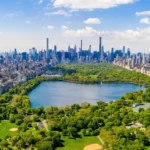 Breed luchtfoto panorama van het groene Central Park met een meer, sportvelden en de wolkenkrabbers van Manhattan aan weerszijden