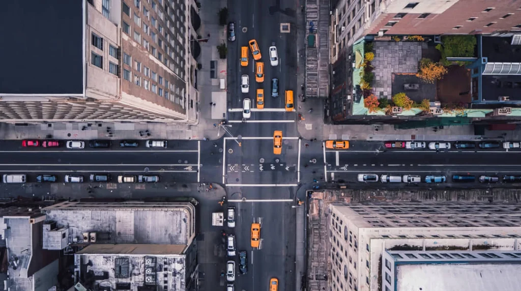 Recht van boven gezien straatkruising in New York met gele taxi's tussen hoge gebouwen en groene daktuinen