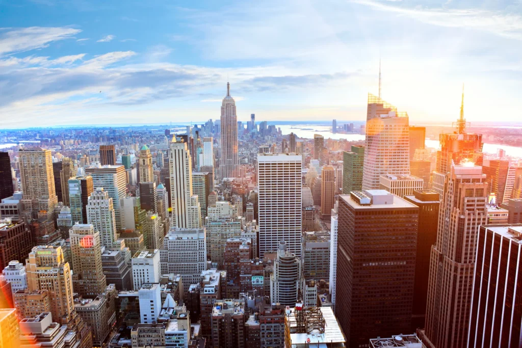 Luchtfoto over de dichte wolkenkrabbers van Manhattan met de Empire State Building in de verte bij zonsondergang