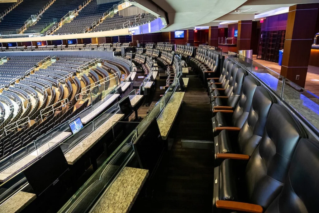 Lederen loungestoelen en een marmeren bar in een luxe skybox met uitzicht op de tribunes van een sportarena