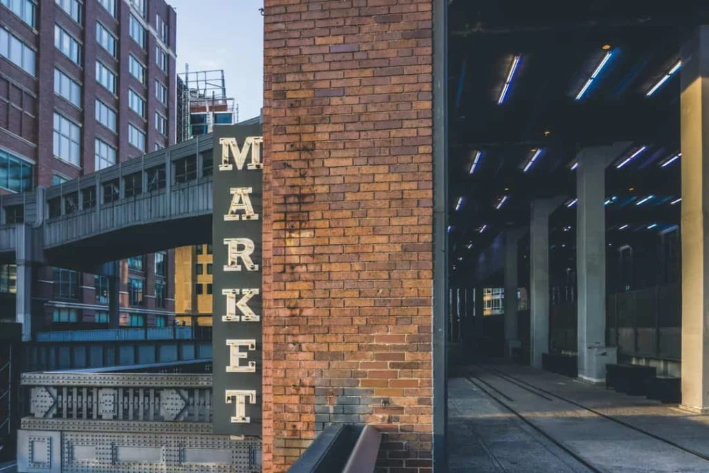 Verticaal market bord op een bakstenen gebouw met een verhoogd spoor op de achtergrond in New York