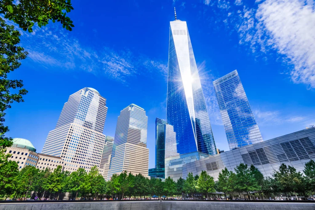 Zwarte memorial vijver omringd door bomen met de glazen toren van One World Trade Center op de achtergrond